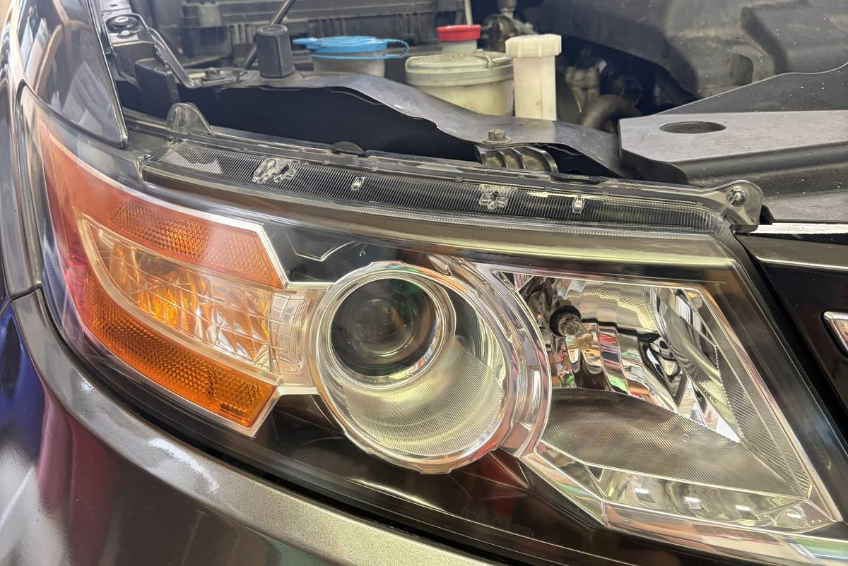 The same Honda Odyssey headlight after restoration: the lens is clear and glossy, and the projector and chrome reflector are sharp