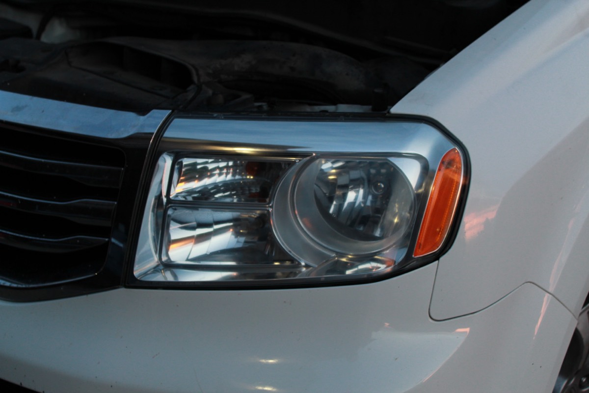 The same Honda Pilot headlight restored to clear, with the projector lens and chrome housing sharply visible