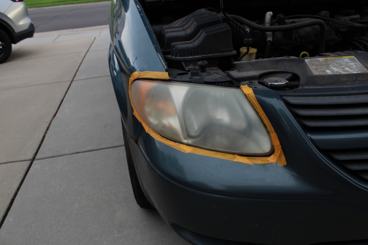 Front quarter view of a green minivan with a clouded, yellow headlight lens
